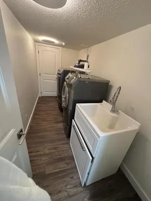 a laundry room with a sink and a washing machine at Luxurious Air Conditioned Inner City Bungalow in Calgary