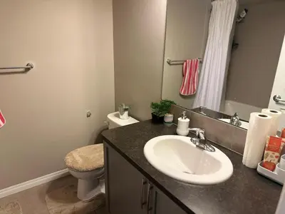 a bathroom with a sink and a toilet at Spacious Bedroom-Near Airport YYC in Airdrie