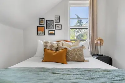 a bedroom with a bed with pillows and a window at The Red Steps Away From World's Largest Dinosaur 3BR House in Drumheller