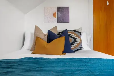 a bed with a bunch of pillows on it at The Red Steps Away From World's Largest Dinosaur 3BR House in Drumheller