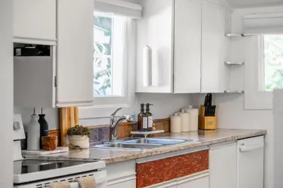 a kitchen with white cabinets and a sink at The Red Steps Away From World's Largest Dinosaur 3BR House in Drumheller