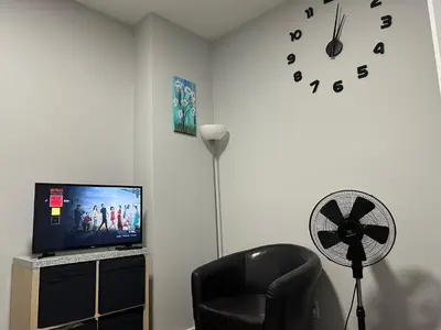 a room with a chair and a clock and a fan at 1-bedroom private suite, 20 minutes from the airport, with a kitchen in Edmonton