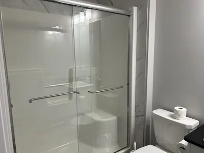 a glass shower in a bathroom with a toilet at 1-bedroom private suite, 20 minutes from the airport, with a kitchen in Edmonton