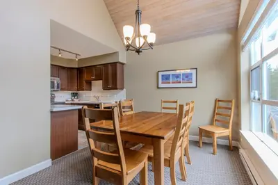 a dining room and kitchen with a wooden table and chairs at The Snowbird by Whiski Jack in Whistler