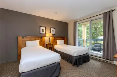 two beds in a room with a window at The Snowbird by Whiski Jack in Whistler
