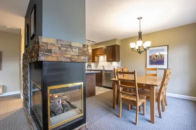 a kitchen and dining room with a fireplace and a table at The Snowbird by Whiski Jack in Whistler