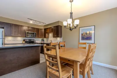 a kitchen and dining room with a wooden table and chairs at The Snowbird by Whiski Jack in Whistler