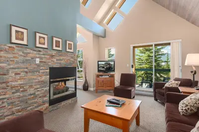 a living room with a fireplace and a tv at The Snowbird by Whiski Jack in Whistler