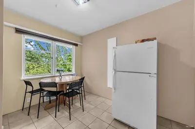 a kitchen with a table and a white refrigerator at Cozy Airb&b Guest Suite Near Metrotown in Burnaby