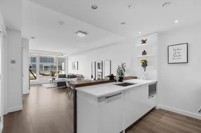 a kitchen and living room with white walls and wood floors at Luxury Waterfront Suite with City Views and AC in Calgary