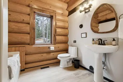 a bathroom in a log cabin with a sink and a mirror at Nordegg Timber Estate in Nordegg