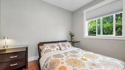 a bedroom with a bed and a dresser and a window at Knockan Hill Rentals - Garden Suite in Victoria