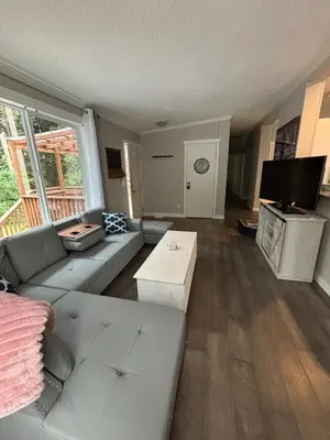 a living room with a couch and a tv at Golfers getaway home in the trees in Roberts Creek