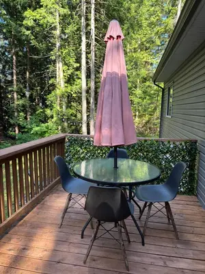 a patio table with an umbrella on a deck at Golfers getaway home in the trees in Roberts Creek