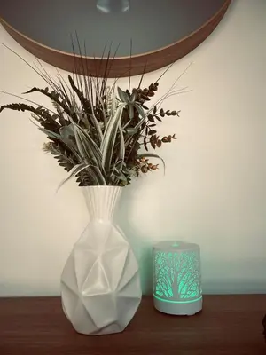 a white vase with a plant in it next to a candle at Castle BNB 2025 in Gibsons
