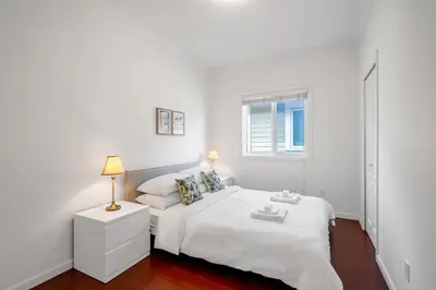 a white bedroom with a white bed and a window at Central Spacious 3 Br Upstairs in Vancouver