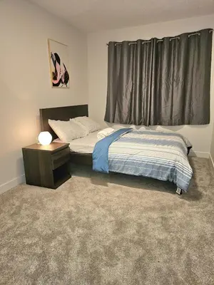 a bedroom with a bed and a table and a window at Family Friendly in Calgary