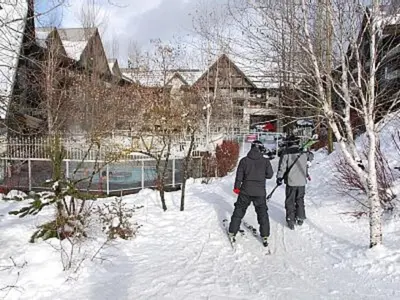 two people on skis in the snow next to buildings at XL Luxury Penthouse Ski-in Ski-out The Aspens in Whistler