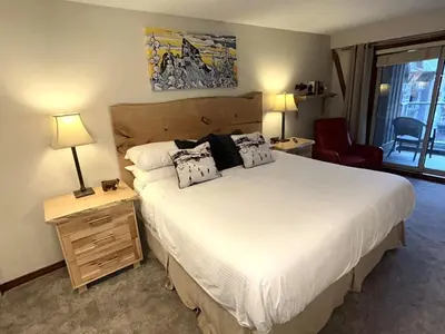a bedroom with a large bed with two lamps and a chair at XL Luxury Penthouse Ski-in Ski-out The Aspens in Whistler