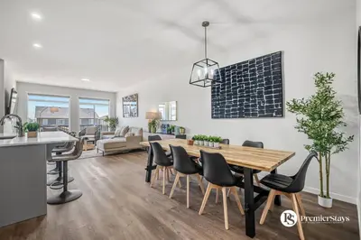 a kitchen and living room with a wooden table and chairs at Executive Single Detached House with AC King Bed and More in Calgary