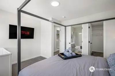 a bedroom with a large bed with a tv on the wall at Executive Single Detached House with AC King Bed and More in Calgary