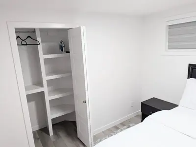 a bedroom with a closet with white shelves at Basement Suite in Desrochers SW in Edmonton