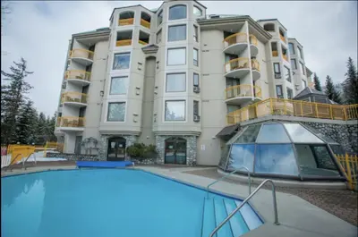 a building with a swimming pool in front of a building at Quiet & Cozy Ski-In Out, Hot tub, pool in Whistler