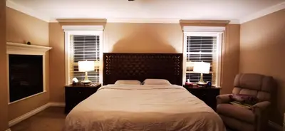 a bedroom with a bed and a chair and two windows at Eagle's House, Room #B in Victoria