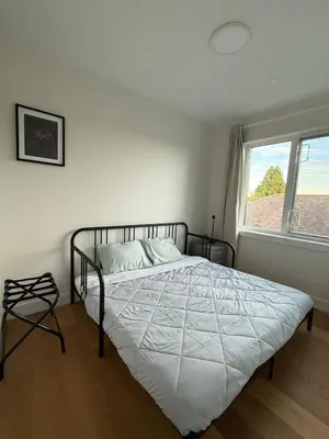 a bedroom with a bed with a white comforter and a window at Roger & May's Cabin in Vancouver