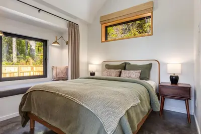 a bedroom with a bed and two windows at Fogged Inn in Ucluelet