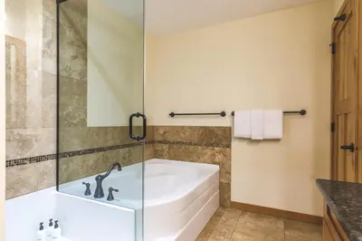 a bathroom with a tub and a glass shower at Creekside at Rundle Cliffs Lodge in Canmore