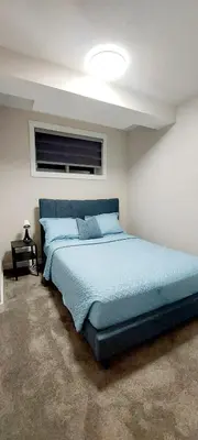 a bedroom with a large bed with a blue comforter at Little Heaven 2BR southwest Calgary in Calgary