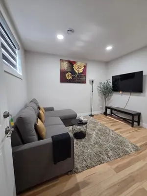 a living room with a gray couch and a flat screen tv at Little Heaven 2BR southwest Calgary in Calgary