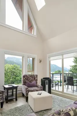 a living room with a couch and a table and windows at Harrison 3BR Pet friendly Unit in Harrison Hot Springs