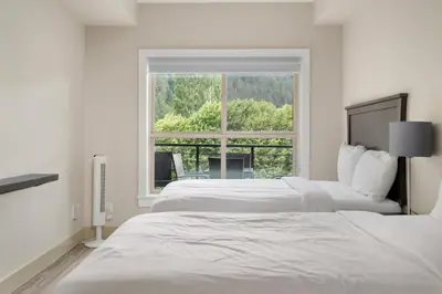 a white bedroom with two beds and a window at Harrison 3BR Pet friendly Unit in Harrison Hot Springs