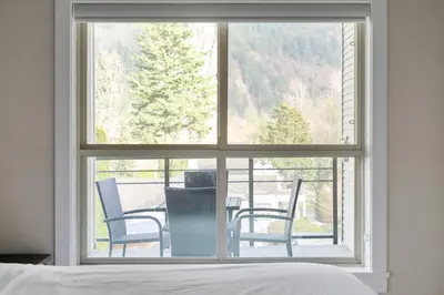 a bedroom window with a view of a table and chairs at 2BR Suite with Scenic Views in Harrison Hot Springs