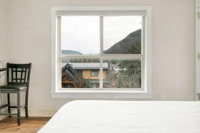 a bedroom with a white bed and a window at Serenity Luxe 2BR unit in Harrison in Harrison Hot Springs