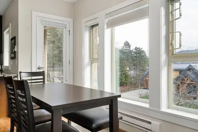 a dining room with a table and two windows at Serenity Luxe 2BR unit in Harrison in Harrison Hot Springs