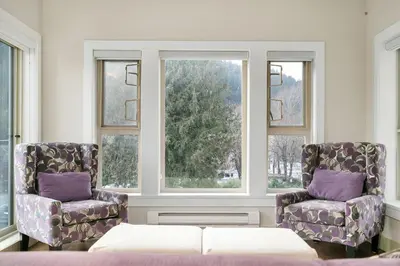 two chairs and a couch in a room with windows at Serenity Luxe 2BR unit in Harrison in Harrison Hot Springs
