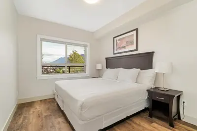 a white bedroom with a bed and a window at Chic Haven Stylish 3Bedroom in Harrison Hot Springs