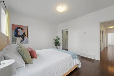 a white bedroom with a large bed and a bathroom at Charming 3 Bedrooms Home with BBQ- Deck- Fenced yard-Near WEM & River Valley in Edmonton