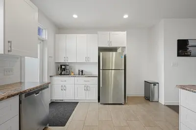 a kitchen with white cabinets and a stainless steel refrigerator at Charming 3 Bedrooms Home with BBQ- Deck- Fenced yard-Near WEM & River Valley in Edmonton