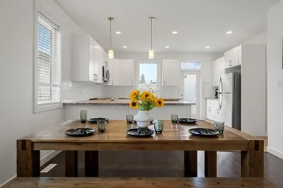 a kitchen with a wooden table with a vase of flowers at Charming 3 Bedrooms Home with BBQ- Deck- Fenced yard-Near WEM & River Valley in Edmonton