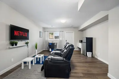 a living room with a black couch and a kitchen at 1 bedroom in Edmonton