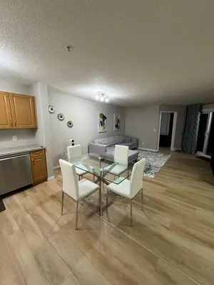 a living room with a glass table and white chairs at The Bloom Haven in Edmonton