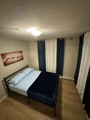 a bedroom with a bed with blue sheets and blue curtains at The Bloom Haven in Edmonton