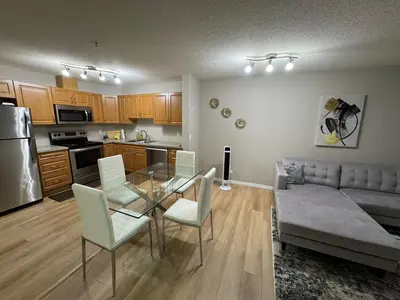 a kitchen and living room with a glass table and a couch at The Bloom Haven in Edmonton