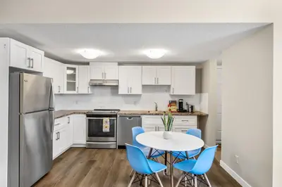a kitchen with white cabinets and a table and blue chairs at 2-bedroom in Edmonton