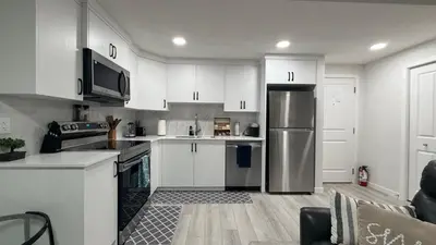 a kitchen with white cabinets and a stainless steel refrigerator at Cozy & Quiet Calgary 2BR Suite in Calgary