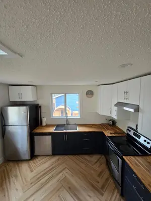 a kitchen with a sink and a stainless steel refrigerator at A Little R and R Private Sauna Cold and Hot Plunge in Calgary